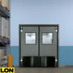 Insulated double swinging door with gasketed edges and vision panels, designed for cold storage or climate-controlled zones to reduce energy loss and maintain air separation