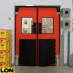 Red USDA/FDA-compliant swinging door with smooth, non-porous panels, vision windows, and impact bumpers, installed in a food or pharmaceutical facility to meet sanitation and OSHA visibility standards