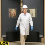 A female meat processing worker exits through a PE-8000 Industrial Door in a USDA-compliant facility, highlighting hands-free traffic flow and durable door design by Traffic Swinging Doors