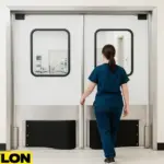 A female veterinary staff member exits through an Industrial Retail Door | PE-620ALC inside a vet clinic, demonstrating how swinging doors in vet clinics improve safety while managing furry patients.