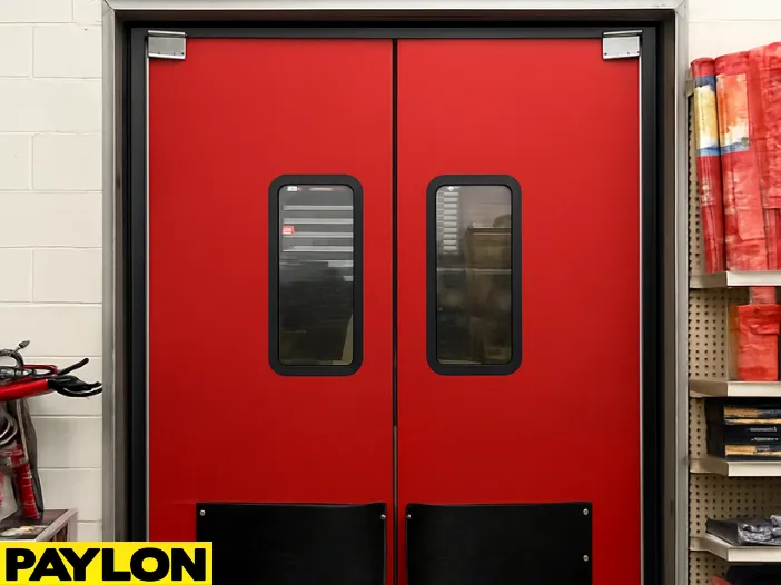 Closed red double-swing industrial door with vision panels – PE-8000 model from Paylon Closed red double-swing industrial door with vision panels – PE-8000 model from Paylon, designed for mid-traffic retail or warehouse environments