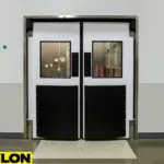 Industrial Double Swinging Door PE-1500 by Paylon – Heavy-Duty White Panels with Black Impact Plates and Windows for High-Traffic Facility Entry