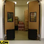 Open PE-1500 industrial swinging doors revealing a busy retail stockroom with stacked boxes and inventory, showcasing clear access and backroom visibility