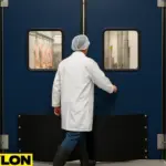 Worker walking through an Industrial Door | PE-9000 inside a meat processing facility – double-swing traffic door with kick plates and vision panels, designed for high-traffic areas