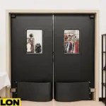 Industrial Door PE-8000 black swinging doors installed in a cosplay studio backroom, surrounded by costumes, wigs, and mannequins for theatrical and costume shop use
