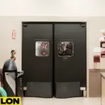 Industrial Door PE-8000 in a tool rental shop, featuring double-action black doors with viewing windows, heavy-duty construction, and a clean, professional environment with visible tools and equipment