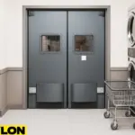 Industrial Door PE-8000 installed in a commercial laundromat, positioned between rows of stainless steel washers and dryers with a laundry cart nearby, perfect for high-traffic access to utility or storage areas while maintaining a clean, professional workflow