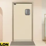 Retail Door PE-710 installed in a boutique clothing store, dividing the backroom from the shopping floor with a sleek beige finish, pastel dresses on a brass rack, and a mannequin display for added style