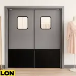 Retail Door PE-720 installed in a boutique clothing store, featuring a sleek gray and black finish, used to stylishly divide the backroom from the sales floor, with pastel dresses on a gold rack and a mannequin display enhancing the neutral décor