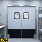 A grey double swinging door with black kick plates installed between stainless steel prep tables in a commercial kitchen