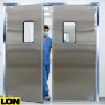 A medical professional in scrubs pushes open one of a pair of aluminum double swinging doors in a hospital