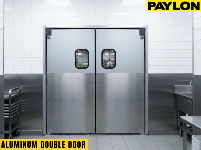 A set of closed aluminum double swinging doors with protective kick plates separating a retail clothing area from a backroom