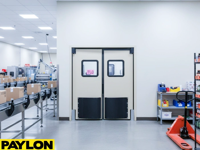 Beige double swinging factory doors in a packaging line area with conveyor belts and storage shelves Beige double swinging factory doors in a packaging line area with conveyor belts and storage shelves