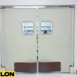 Beige impact swinging doors with small vision panels in a healthcare facility