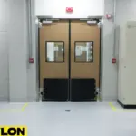 Brown industrial swinging doors separating work zones in a clean, controlled factory environment