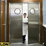 Chef carrying glassware through stainless steel swinging kitchen doors in a restaurant food prep area