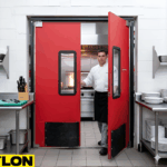 Chef entering a commercial kitchen through red double swinging doors with vision panels and kick plate