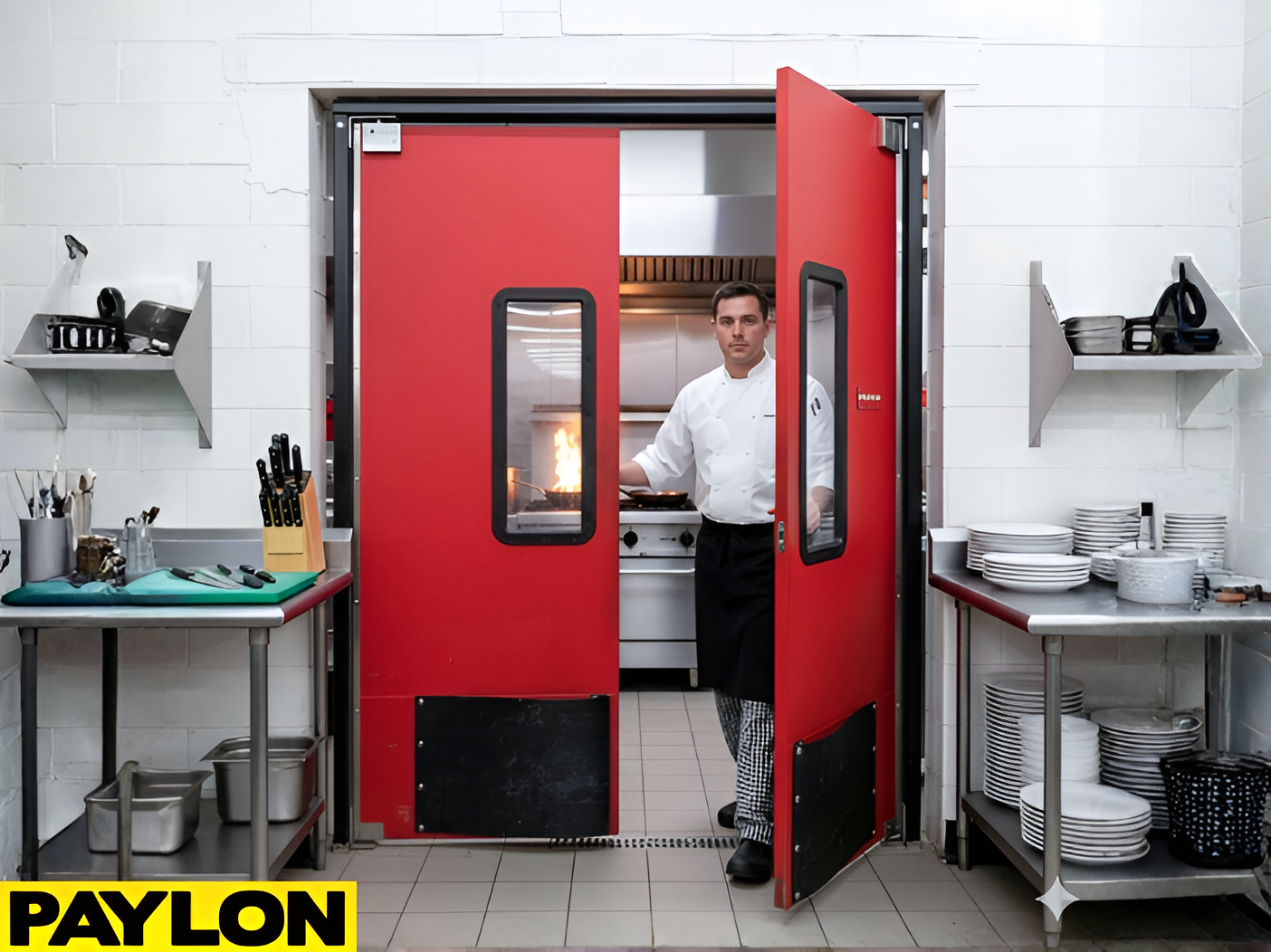 Chef entering a commercial kitchen through red double swinging doors with vision panels and kick plate