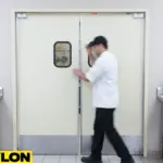 Chef walking through beige PE-Series kitchen swinging traffic doors in a commercial kitchen