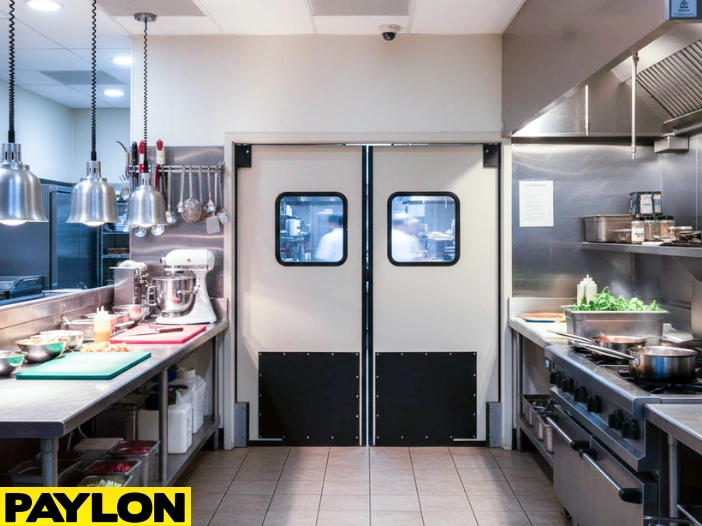 Clean commercial kitchen with double beige swinging doors demonstrating how to choose the right door for your backroom, breakroom, or prep area