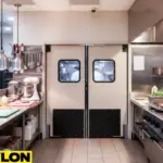Clean commercial kitchen with double beige swinging doors demonstrating how to choose the right door for your backroom, breakroom, or prep area