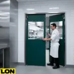 Clear Impact Swinging Door with green panels in a commercial kitchen, opened by chef for easy workflow