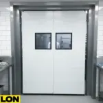 Closed white PVC commercial food swinging doors with vision panels in a professional kitchen