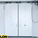 Double insulated white sliding freezer doors with overhead track system in industrial cold storage facility