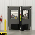 Gray double swinging doors with vision panels in a warehouse entrance, worker exiting for industrial safety access