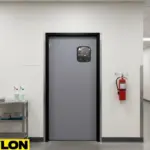 Gray single swinging door with vision panel in a clean facility hallway, suitable for controlled access areas