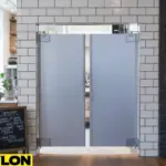 Gray swinging café doors installed in a modern café with tiled walls and wooden decor Gray swinging café doors installed in a modern café with tiled walls and wooden decor