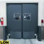 Heavy-duty gray industrial swinging doors with bumpers in a warehouse environment Heavy-duty gray industrial swinging doors with bumpers in a warehouse environment