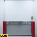 Heavy-duty sliding freezer door with diamond plate paneling and safety bollards in a cold storage room.