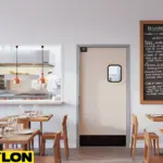 Light beige single swinging door by Paylon connecting a restaurant dining area to the kitchen, designed with a small vision window and kick plate for smooth service flow
