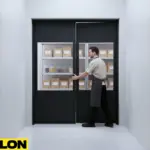 PE-400 Clear Impact Swinging Door being opened in a stockroom, demonstrating hands-free two-way swing and durability