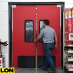 Red industrial swinging doors with black kick plates in a busy retail stockroom Red industrial swinging doors with black kick plates in a busy retail stockroom