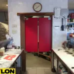 Red pizza parlor swinging doors in a compact restaurant kitchen separating prep and cooking areas Red pizza parlor swinging doors in a compact restaurant kitchen separating prep and cooking areas