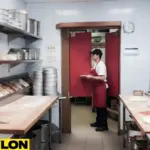 Staff member carrying a plate through red café-style swinging doors in a restaurant kitchen with pizza ingredients on the counters Staff member carrying a plate through red café-style swinging doors in a restaurant kitchen with pizza ingredients on the counter