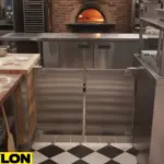 Stainless steel café-style pizza parlor swinging doors leading to a prep area with brick oven in the background Stainless steel café-style pizza parlor swinging doors leading to a prep area with brick oven in the background.