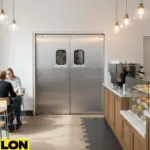 Stainless steel swinging doors in a modern café separating kitchen and dining area