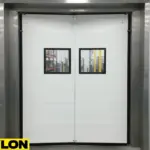 White Clear Impact Swinging Door installed in a warehouse, showing visibility panels and industrial-grade construction