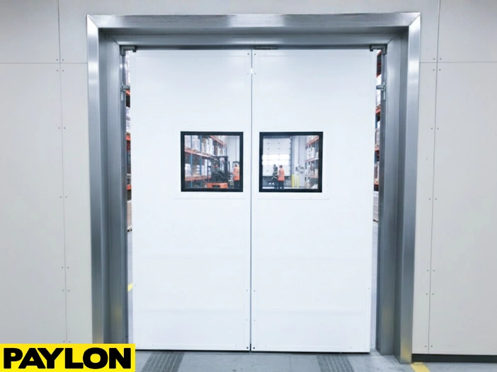 White commercial PVC swinging doors with vision panels in a warehouse setting White commercial PVC swinging doors with vision panels in a warehouse setting