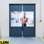 Worker passing through commercial PVC swinging doors at a loading dock facility Worker passing through commercial PVC swinging doors at a loading dock facility