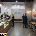 Busy coffee shop with staff moving through retail swinging doors behind counter