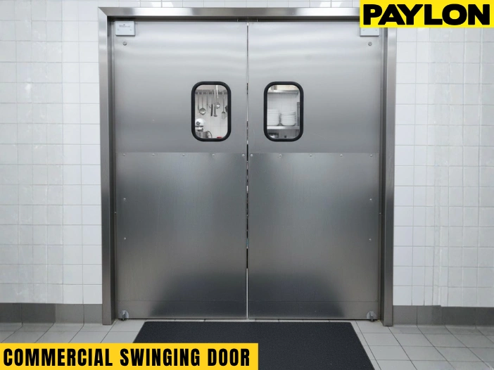 Chef carrying food through a PE-Series commercial swinging door inside a clean, stainless steel kitchen workspace