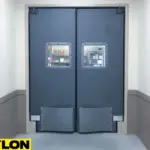 Dark gray PE-8000 industrial swinging doors designed for warehouses or cold-storage areas with heavy-duty impact plates and sealed construction