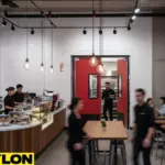 High-traffic café with staff and customers passing through gray retail swinging doors