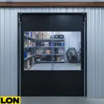 Paylon black double action swing doors installed in a warehouse, featuring clear vision panels for safe and efficient workflow