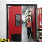 Paylon red industrial double doors in a manufacturing facility with worker entering production area