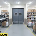 Back-room parcel storage area with heavy-duty dark gray swinging doors designed for high-volume staff movement and cart access.